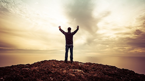 Mand rækker hænderne ud mod horisonten